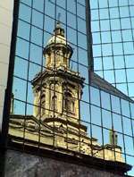 Santiago has old and new alike, as demonstrated by the reflection of an old church in the mirror windows of a modern building.